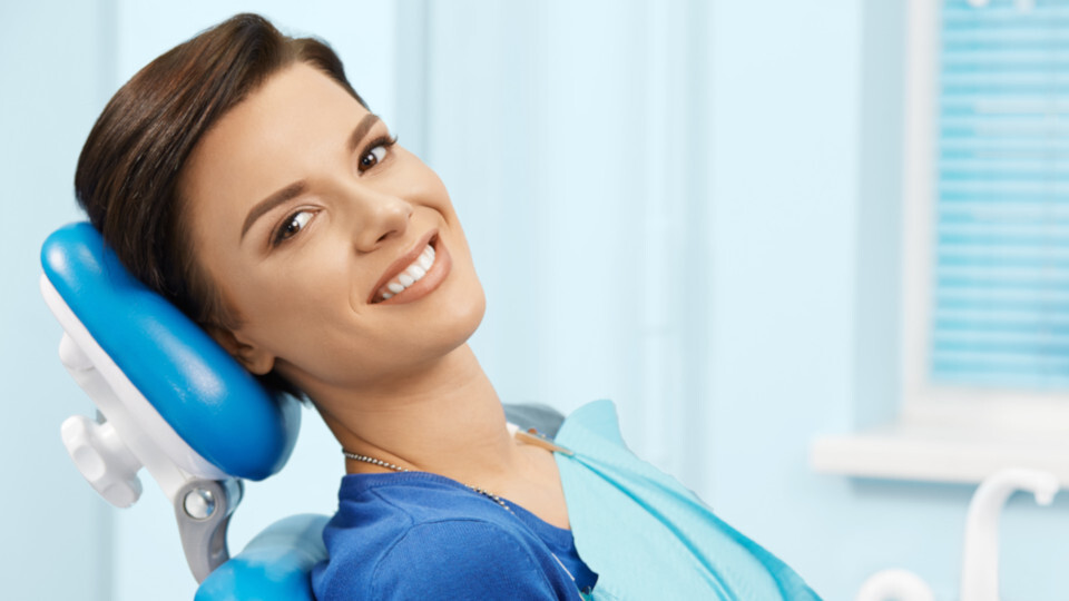 Eine Frau lächelnd auf einem Zahnarztstuhl
